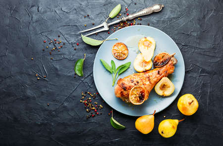 Baked turkey leg with caramelized pear.Appetizing meat dish.の写真素材