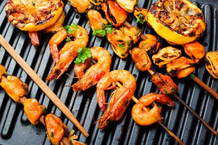 Delicious roasted shrimps and mussels on wooden skewersの写真素材