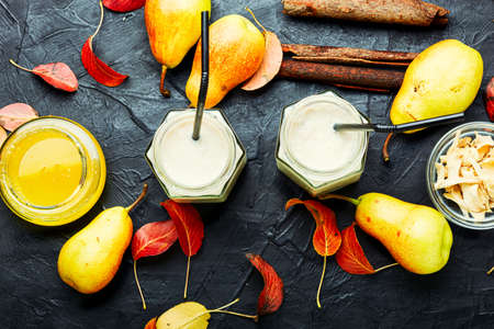 Autumn fruit drink.Pear and ginger smoothie and fallen leavesの写真素材