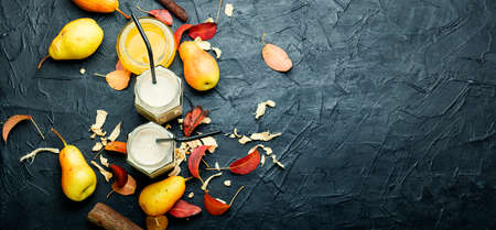 Pear and ginger smoothie and fallen leaves.Jar of fruit smoothies.Copy spaceの写真素材