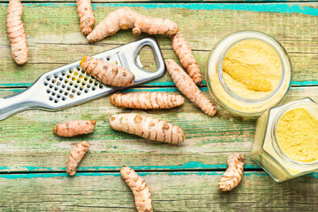 Fresh turmeric root and turmeric powder on wooden tableの写真素材