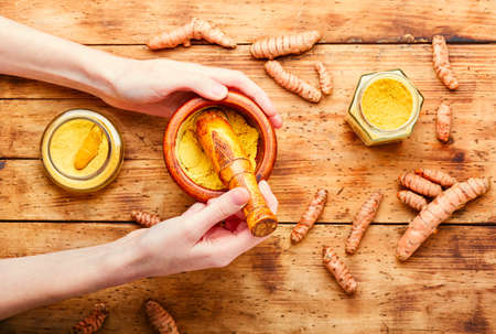Fresh turmeric root and turmeric powder on wooden tableの写真素材