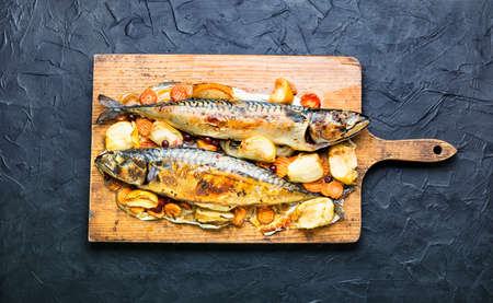 Delicious mackerel fish baked with apples, served on a kitchen board.