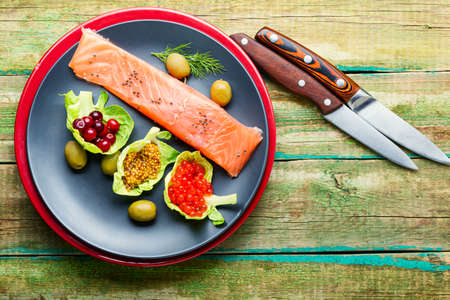 Salted salmon with red caviar and cranberries on wooden tableの写真素材