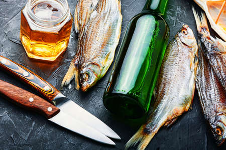 Dried fish on the table, salty dry sea fish for beer.Glass of beer and dried fishの写真素材