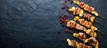 Fried turkey meat with apple on wooden skewers.Appetizing barbecue.Space for textの写真素材