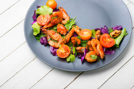 Appetizing fresh salad with shrimps, tomato and lettuce on a plate.