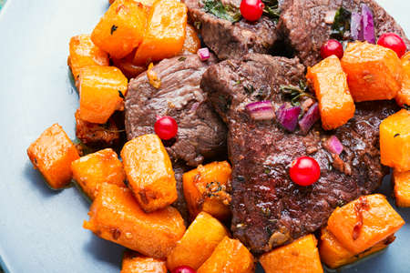 Beef steaks cooked with pumpkin pieces.Veal meat with cranberry sauce.の写真素材
