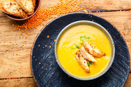 Plate of vegetarian red lentil soup on wooden tableの写真素材