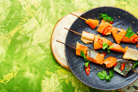 Kebabs from dried and salmon on wooden skewers. Delicious smoked fishの写真素材