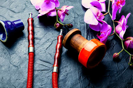 Hookah mouthpiece and hookah cup on pink orchid background.Kalian on flower tobaccoの写真素材