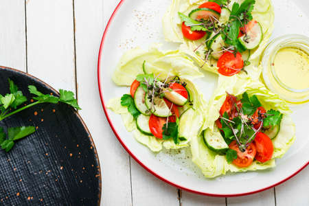 Plate of green salad with summer vegetables. Salad with cabbage, cucumber, tomato and herbs. Healthy vegetable saladの写真素材