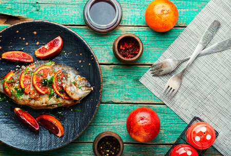 Grilled spicy dorado fish with grapefruit.Roasted fish on old wooden tableの写真素材