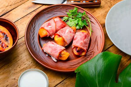 Tamarillo pieces wrapped and baked with ham and baconの写真素材