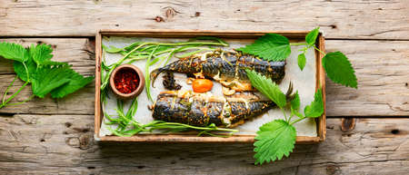Baked mackerel with tarragon and nettle.Cooked scomber in herbs on a wooden trayの写真素材