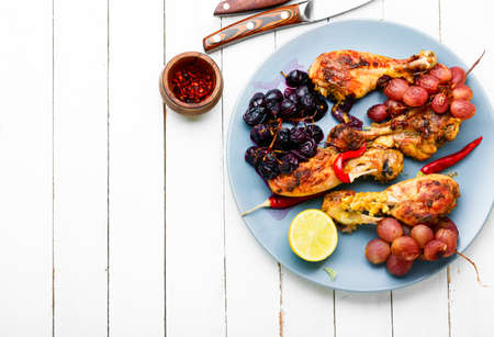 Baked chicken legs with grapes on white wooden backgroundの写真素材