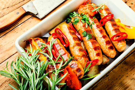 Fried sausages with potatoes and vegetables in a baking dishの写真素材