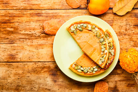 Fresh homemade pumpkin pie on wooden table.Pumpkin tart.Thanksgiving pumpkin cakeの写真素材