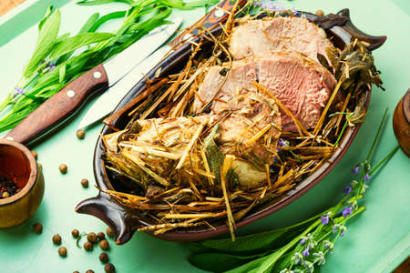 Delicious meat roasted in fresh hay. Baked pork meat in spicy herbs.Autumn foodの写真素材