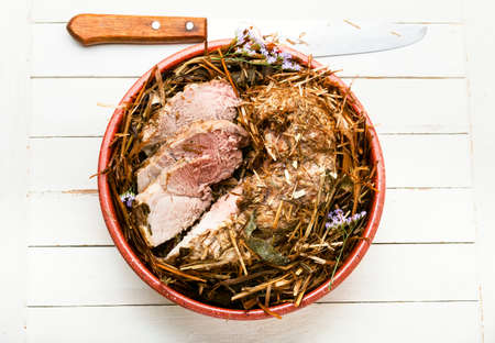 Delicious meat roasted in fresh hay. Baked pork meat in spicy herbs.Autumn foodの写真素材
