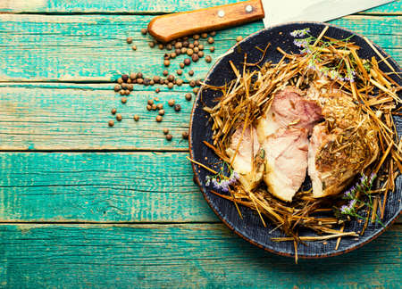 Meat roasted in fresh hay. Baked pork meat in spicy herbs.Autumn food.Copy spaceの写真素材