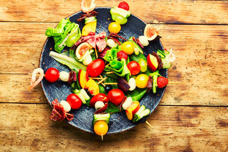 Buffet appetizer of shrimps, jamon, fruits and vegetables on wooden skewers.Flat layの写真素材