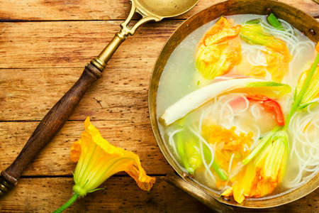 Soup with rice noodles and pumpkin flowers. Asian vegan soup.の写真素材