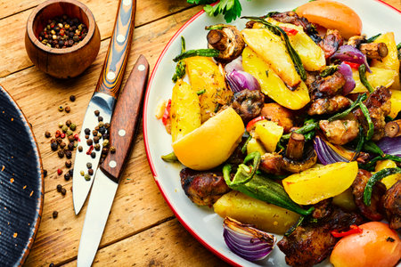 Baked meat with potatoes, apples, mushrooms and okra. Roasted meat with vegetables on the plateの写真素材