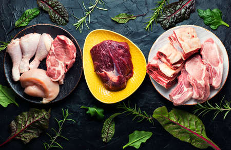 Set of fresh raw meat. Beef, pork and chicken meat on the kitchen table.の写真素材