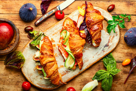 Fresh croissants,healthy breakfast on the kitchen board.Croissants with trout, meat bacon, vegetables and fruitsの写真素材