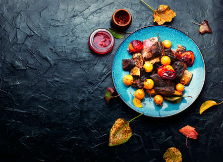 Beef ribs baked in plums and pears.Meat ribs grilled in fruit sauce on the plate.Copy spaceの写真素材