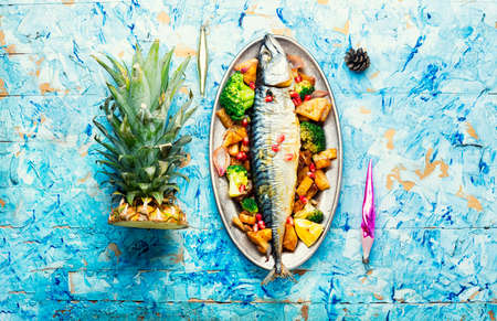 Baked whole fish with pineapple, broccoli and pomegranate. Grilled mackerelの写真素材