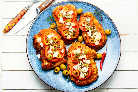 Thin layer of meat, breaded in breadcrumbs with cheese, olives and tomato. Meat dish - schnitzelの写真素材