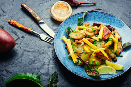 Healthy grilled chicken meat garnished with mango and greens. Tasty meat salad.