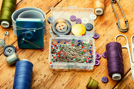 Threads, needles, buttons, seamstress tools. Sewing accessories on retro wooden table