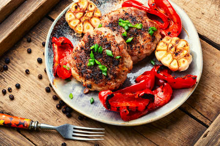 Fried rissole with minced meat and garnish of roasted bell pepper and garlicの写真素材