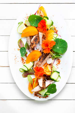 Sliced pork steak with vegetable garnish and garnished with flowers.の写真素材