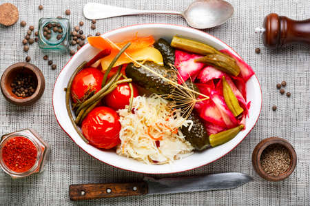 Homemade pickled cucumbers, okra, bell peppers, tomatoes and sauerkraut. Appetizing pickles, canned vegetablesの写真素材