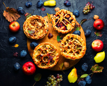 Assortment of autumn fruit pie or tartlet.Pie baked of apples,pears,grapes and plums.Top viewの写真素材