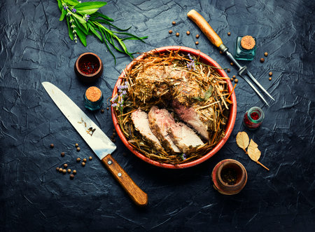 Delicious meat roasted in fresh hay. Baked pork meat in spicy herbs.Autumn foodの写真素材