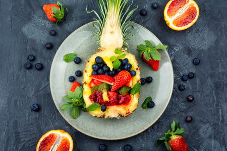 Delicious fruit salad of strawberries, kiwi, berries and orange in half a pineapple. Making fruit saladの写真素材