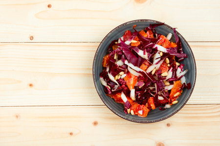 Fresh salad with chicory, grapefruit and pine nuts on a plate. Healthy food, top view. Copy spaceの写真素材