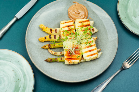 Healthy dish of white asparagus, grilled halloumi cheese decorated with microgreens.の写真素材