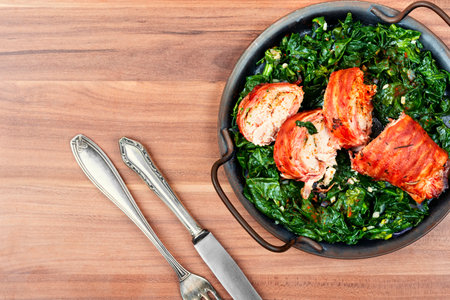 Baked chicken roll with fried spinach leaves. Space for textの写真素材