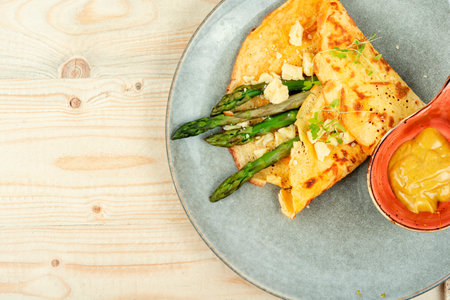 Appetizing egg omelet with green asparagus, sauce and herbs. Copy space.の写真素材