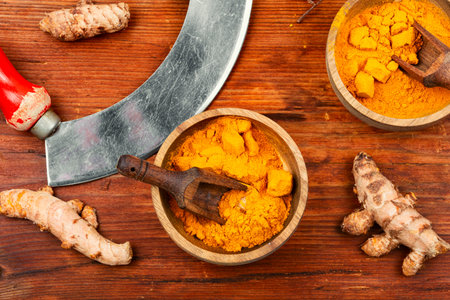 Raw turmeric root and turmeric powder on a wooden background.の写真素材