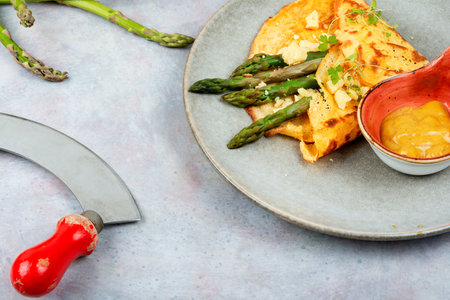 Fried egg omelet stuffed with green asparagus and herbs.の写真素材