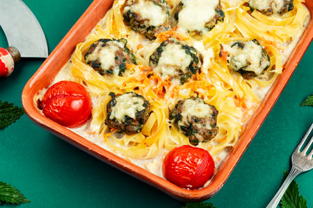 Meatballs served over appetizing noodles in baking dish.の写真素材