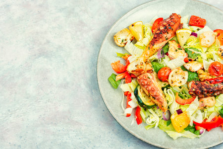 Delicious salad of fresh vegetables, herbs and fried octopus tentaclesの写真素材