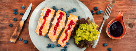 Baked salmon fish with blueberry berry sauce. Salmon fillets, grilled steaks on a wooden table. Top view.の写真素材